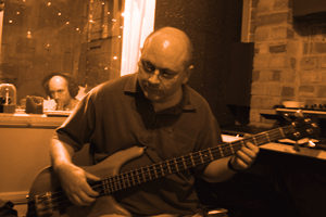 Photo of Eric laying down the bass guitar, with Carlos in the background