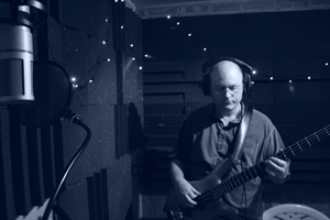 Photo of Eric recording bass guitar in the recording booth